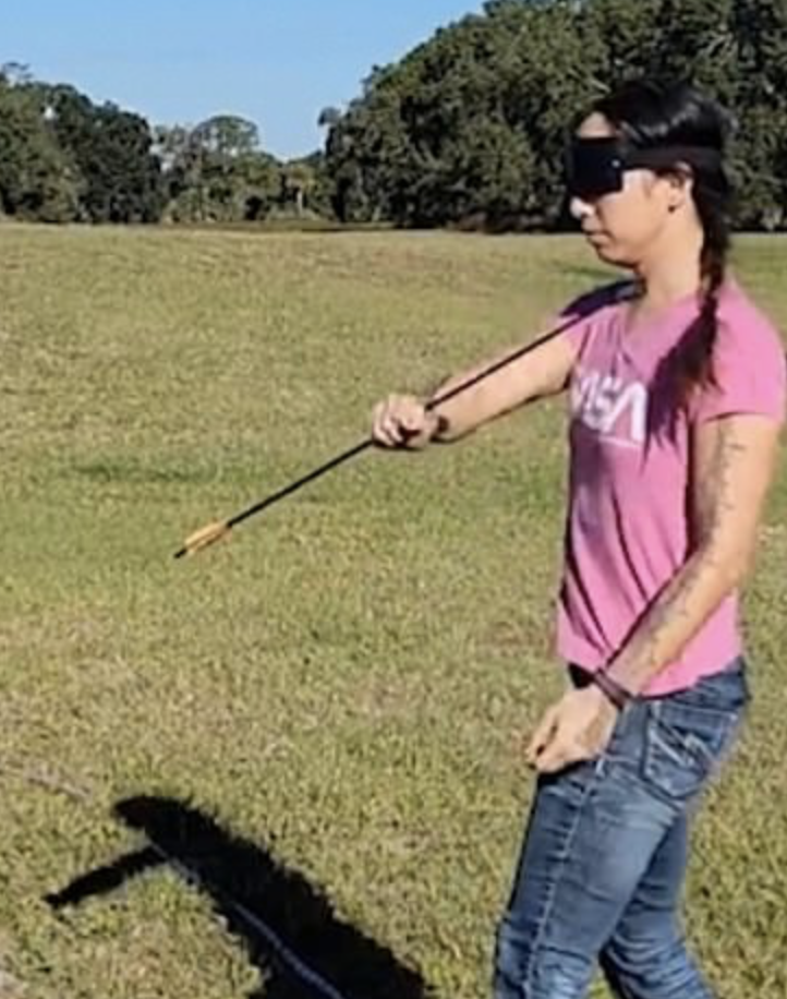 Blindfolded performer catches a flying arrow in one hand after firing it with a crack of her whip
